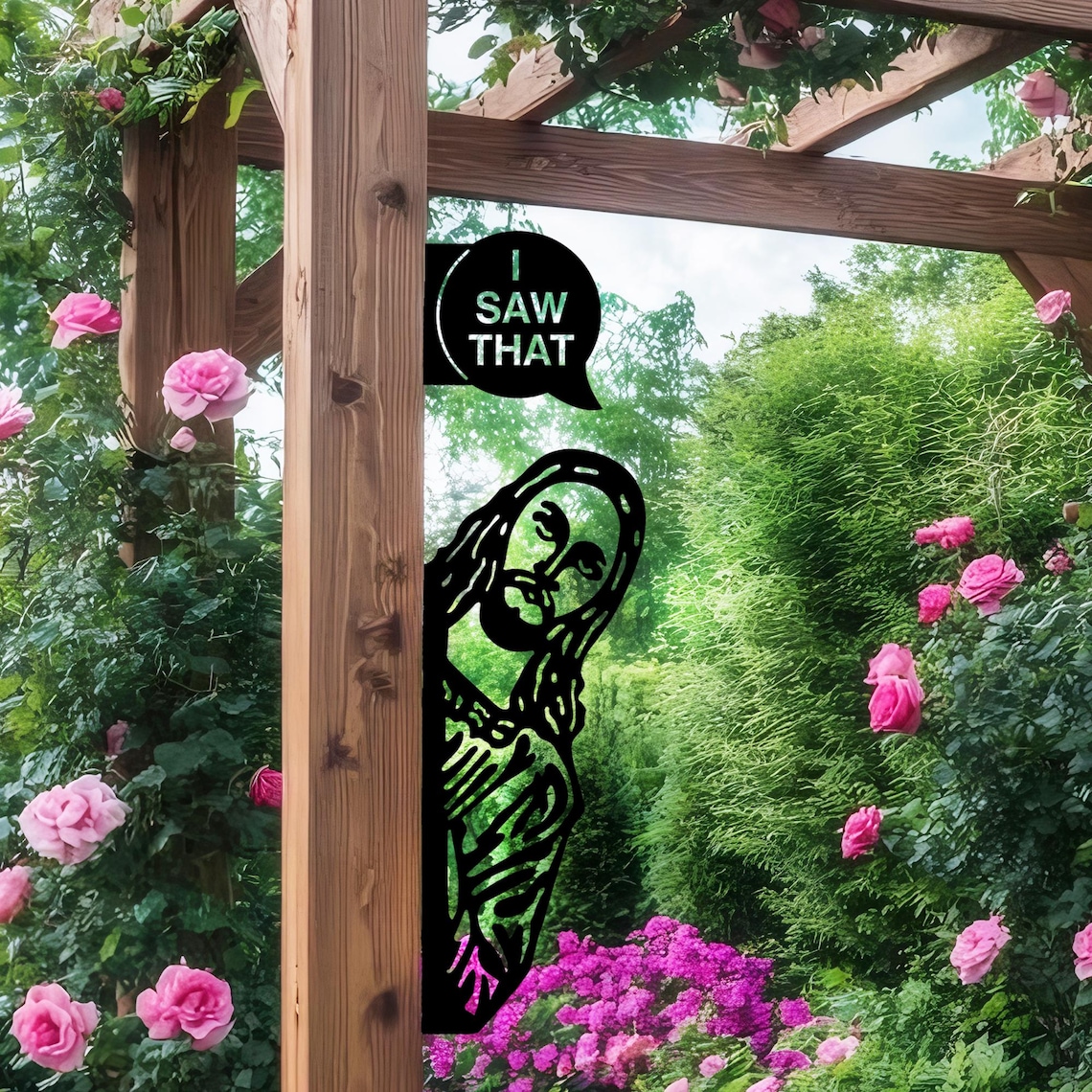 May include: A black metal garden art piece featuring a silhouette of Jesus peeking from behind a wooden post. Above, a speech bubble reads "I SAW THAT". The background includes a lush garden with pink roses and green foliage.