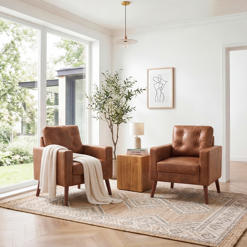 Pair of mid-century brown leather luxury sofa chairs with a white throw blanket in a bright modern living room.