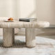 Affordable coffee table close-up showing natural travertine stone surface and rounded legs with books and décor on top
