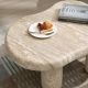 Affordable coffee table detail showing smooth travertine stone tabletop with rounded edge and natural veining
