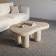 Affordable coffee table with natural travertine stone top and rounded legs in a modern minimalist living room
