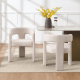 Two ivory white dove luxury dining chairs shown from the front and back at a marble dining table.
