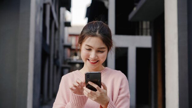 Free photo cheerful asian backpacker blogger woman using smartphone for direction and looking on location map while traveling at chinatown in beijing, china. lifestyle backpack tourist travel holiday concept.