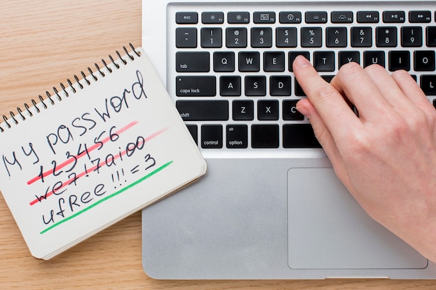 Free photo flat lay of laptop with hands and notebook with password information