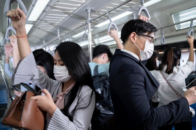 Photo business people standing in metro mass transit subway. man using tablet and smartphone. people wearing face mask. coronavirus flu virus in public travel.