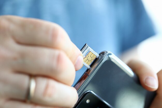 Photo male hands getting sim card slot of his smartphone out closeup