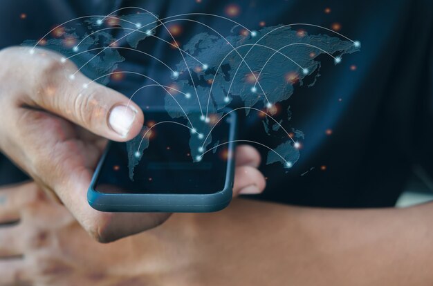 写真の男性がスマートフォンを手に持っています。世界中の携帯電話や現代のソーシャルネットワークでコミュニケーションをとっています。この画像の要素はNASAによって提供されています。