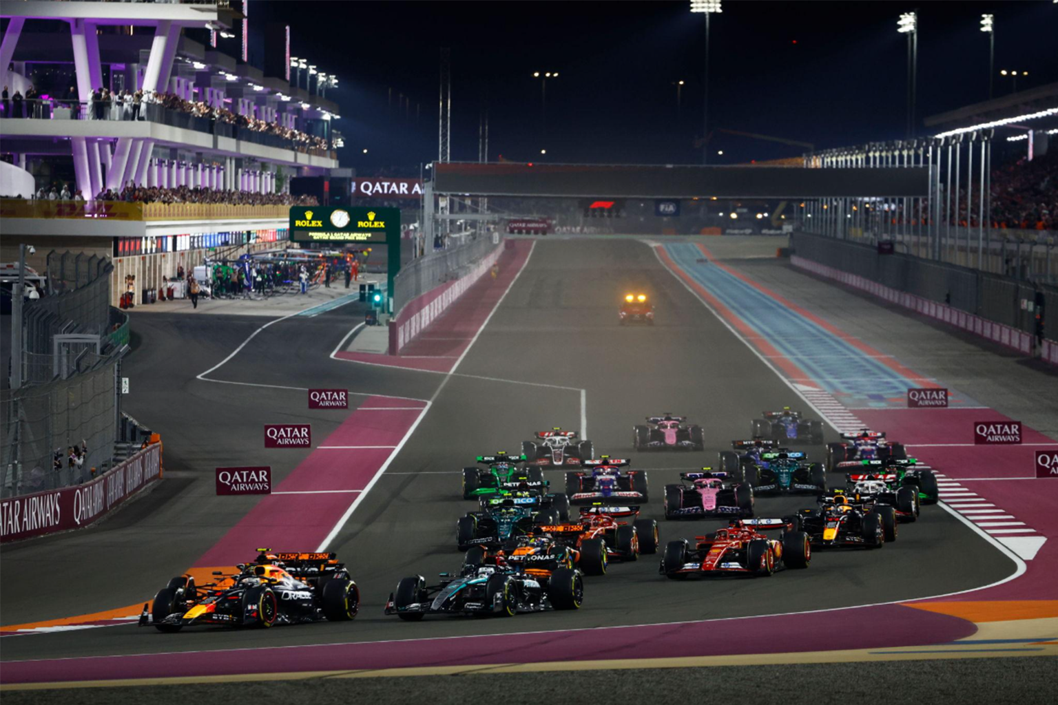 Monoplazas de Fórmula 1 al inicio de una carrera nocturna en el Circuito Internacional de Lusail, en Catar