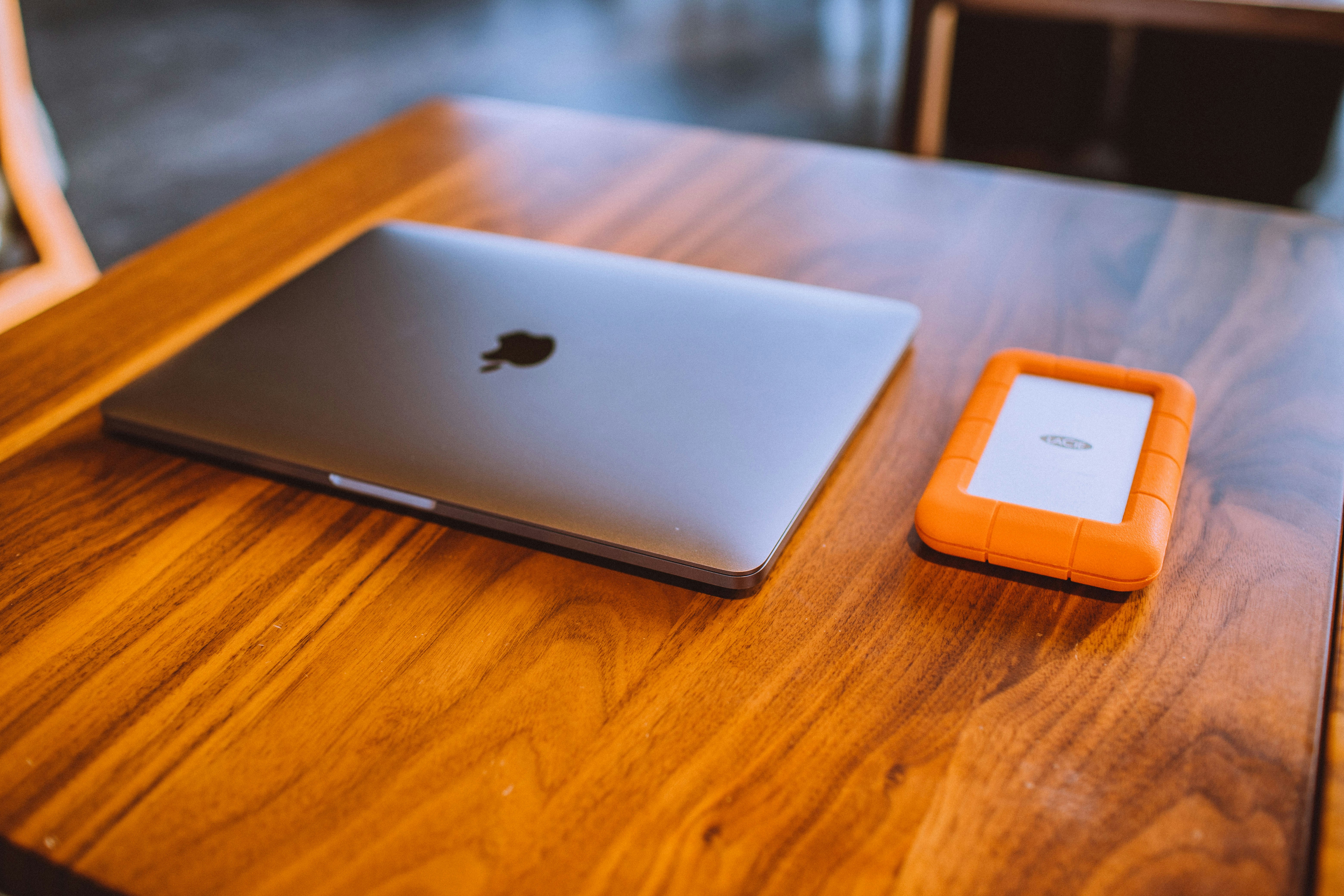 MacBook on a wooden table next to a phone