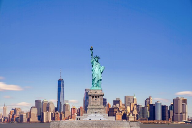 Photo the statue of liberty with the one world trade building center over hudson river and new york cityscape background, landmarks of lower manhattan new york city.