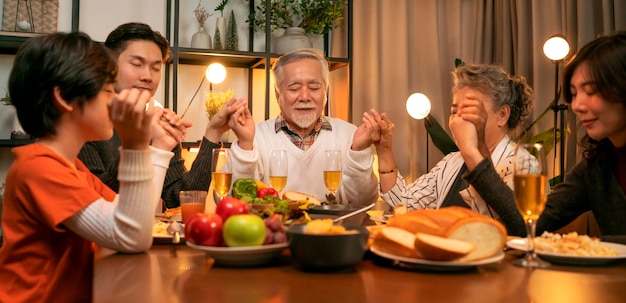 Free photo happiness asian multi generation dining togetherfamily holding hands and praying on thanksgiving before holiday dinnergrandparent grandchildren stay together in thanksgiving traditional dinner home