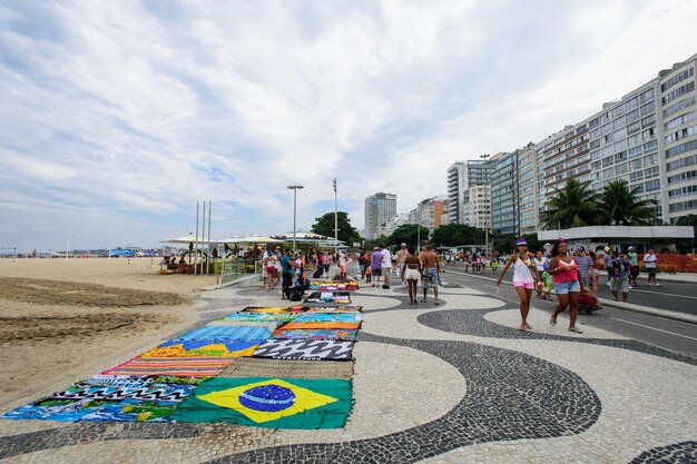 Photo rio de janeiro - march 8: copacabana on march 8, 2012 in rio de janeiro. people relax on sidewalk in copacabana. on weekends avenue near beach is closed for traffic and became a leisure place