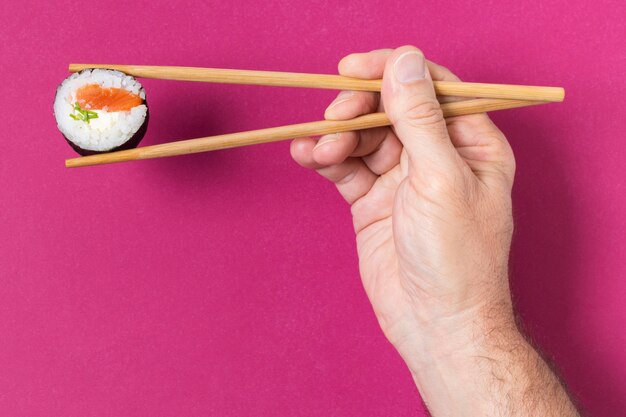 Free photo hand with chopsticks and sushi