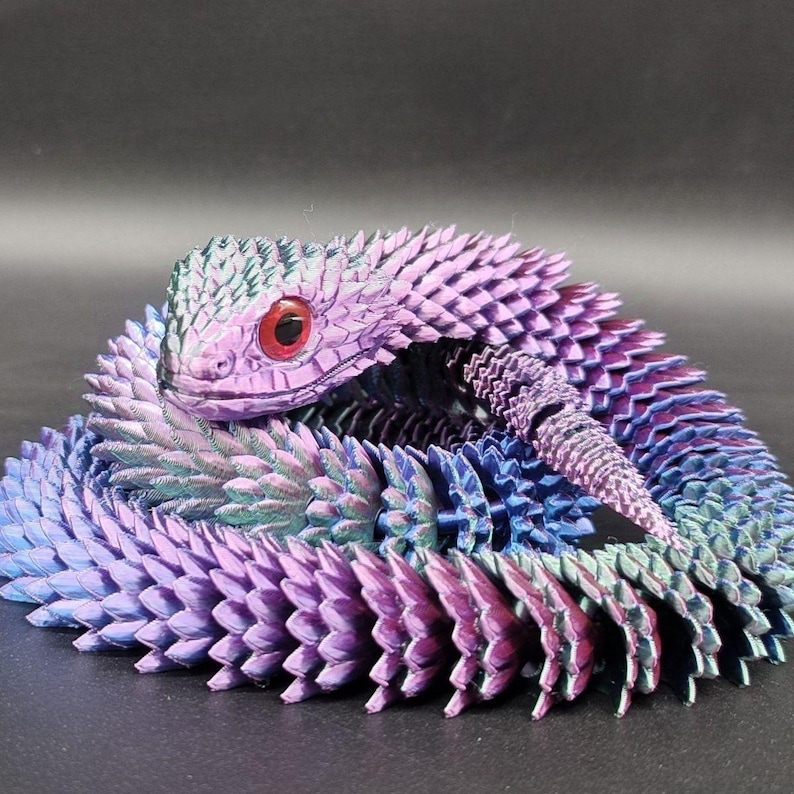 可能包括：精心制作的 3D 打印鳞片爬行动物模型的特写，该模型盘绕成圆形。该模型展示了鲜艳的紫色、蓝色和青色鳞片，头部细节丰富，眼睛呈红色。复杂的细节和色彩过渡营造出视觉冲击效果，凸显了 3D 打印和绘画工艺的精湛技艺。爬行动物的鳞片大小均匀，排列整齐，表明模型的构造非常精确。整体美感是幻想或神话生物的设计，色调和鳞片纹理营造出一种超凡脱俗的美感。