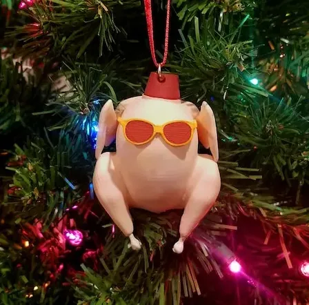 May include: A white turkey ornament with red and yellow sunglasses and a red fez hat. The ornament is hanging on a green Christmas tree with colorful lights.