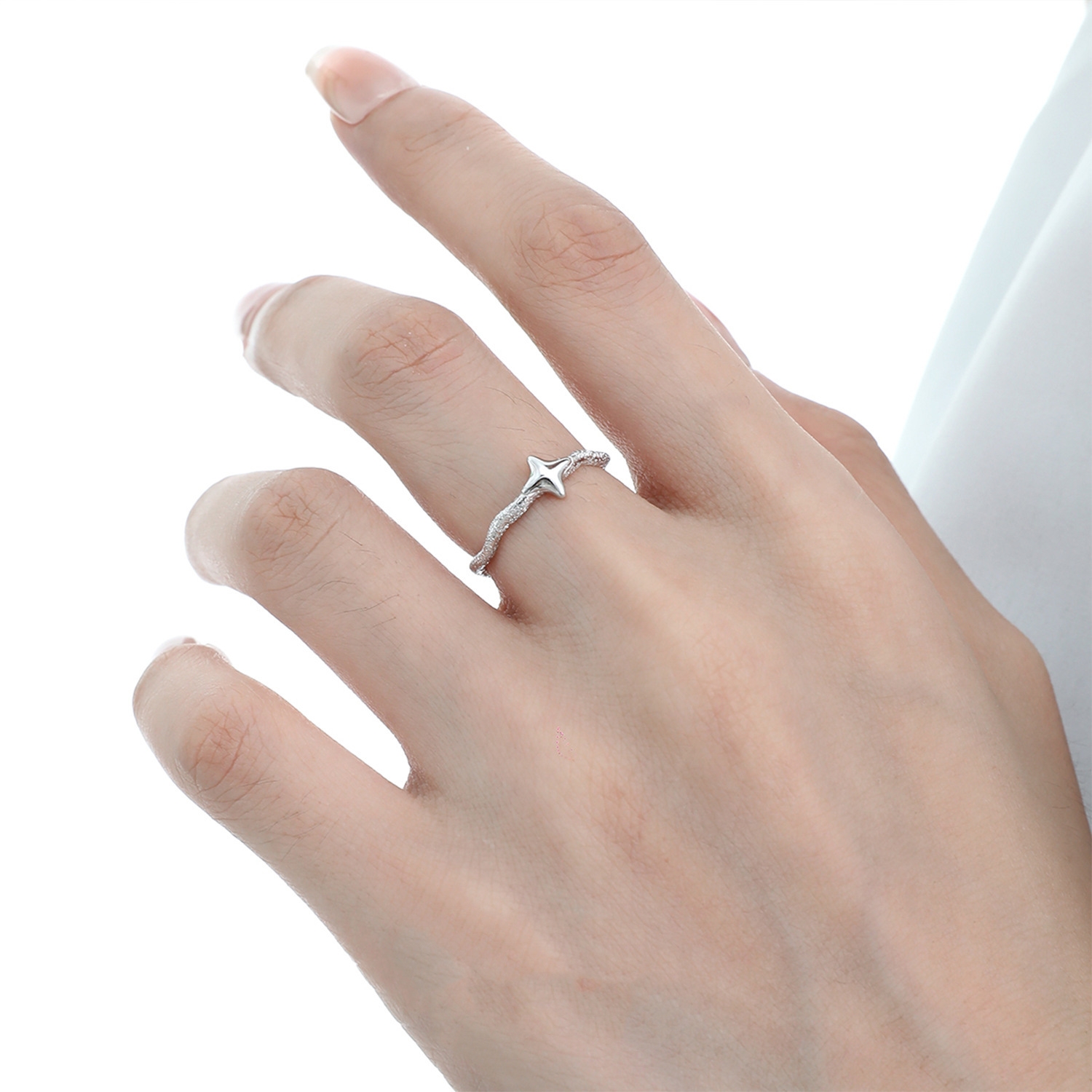 Close-up of Starla N°6 sterling silver zircon star ring worn on finger, white zircon four-point star catching light