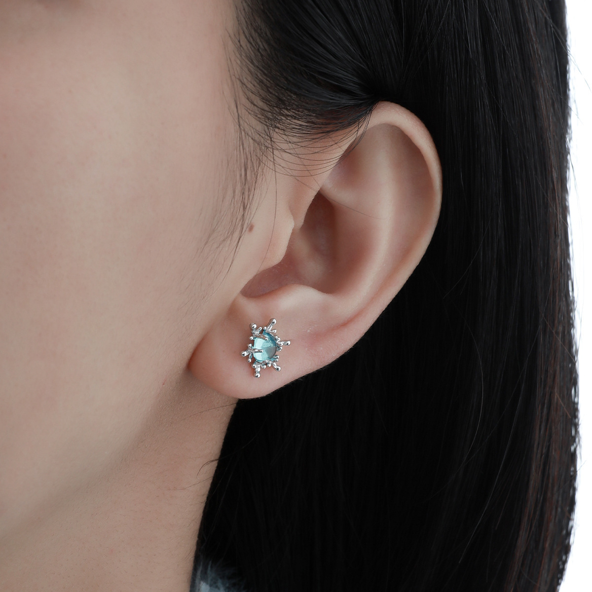 Blue snowflake silver stud earring worn on woman