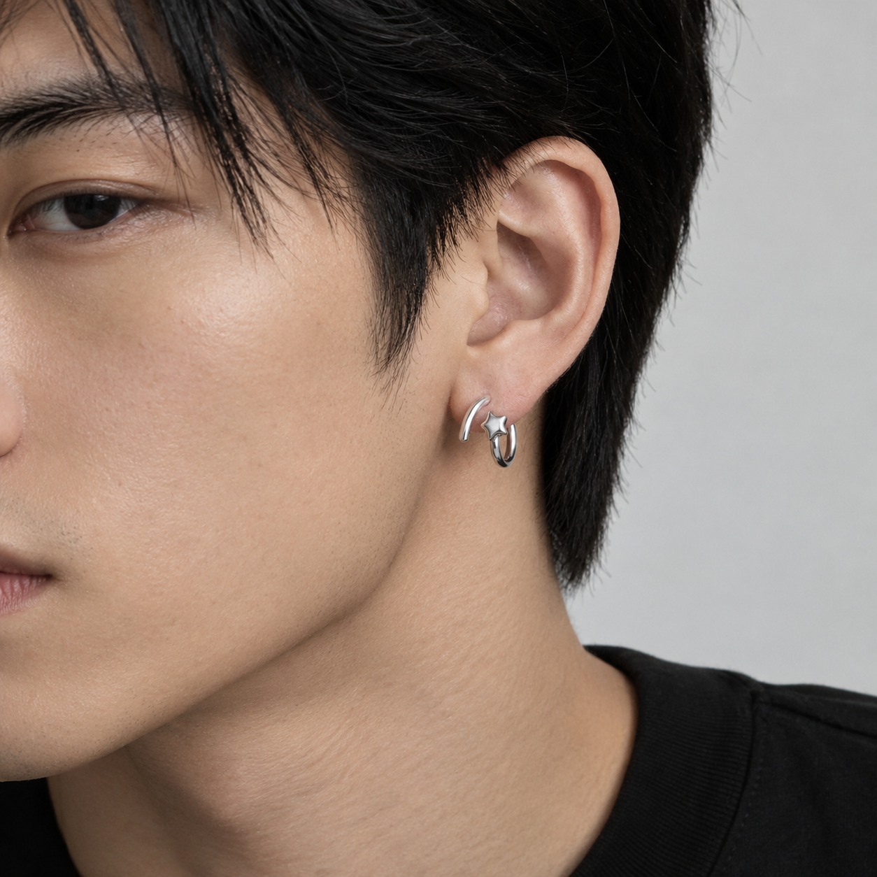 Dara N°9 silver star earrings styled on a man's ear