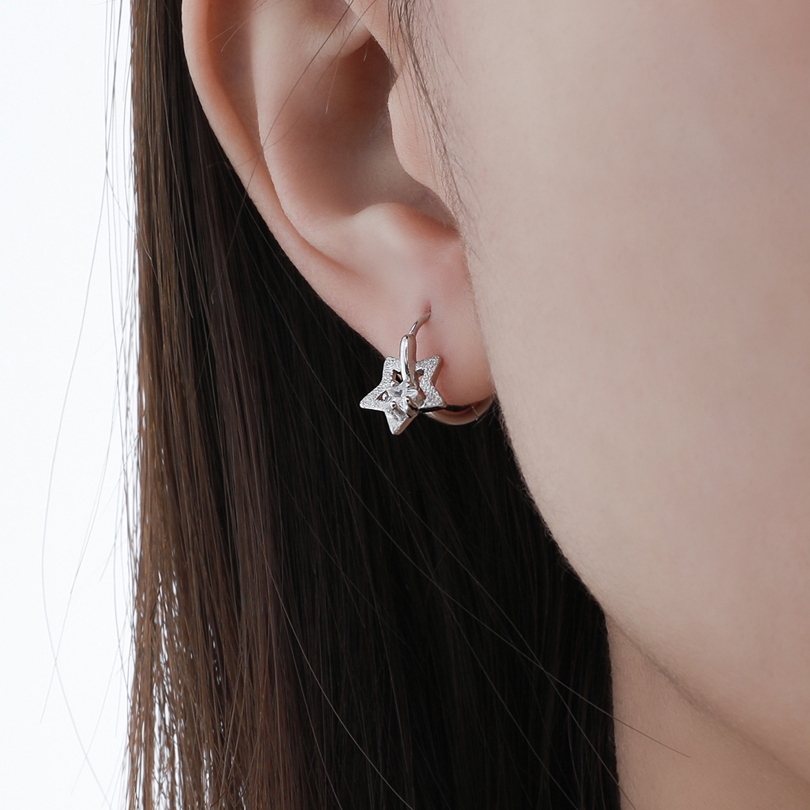 Delicate sterling silver star hoop earring on ear