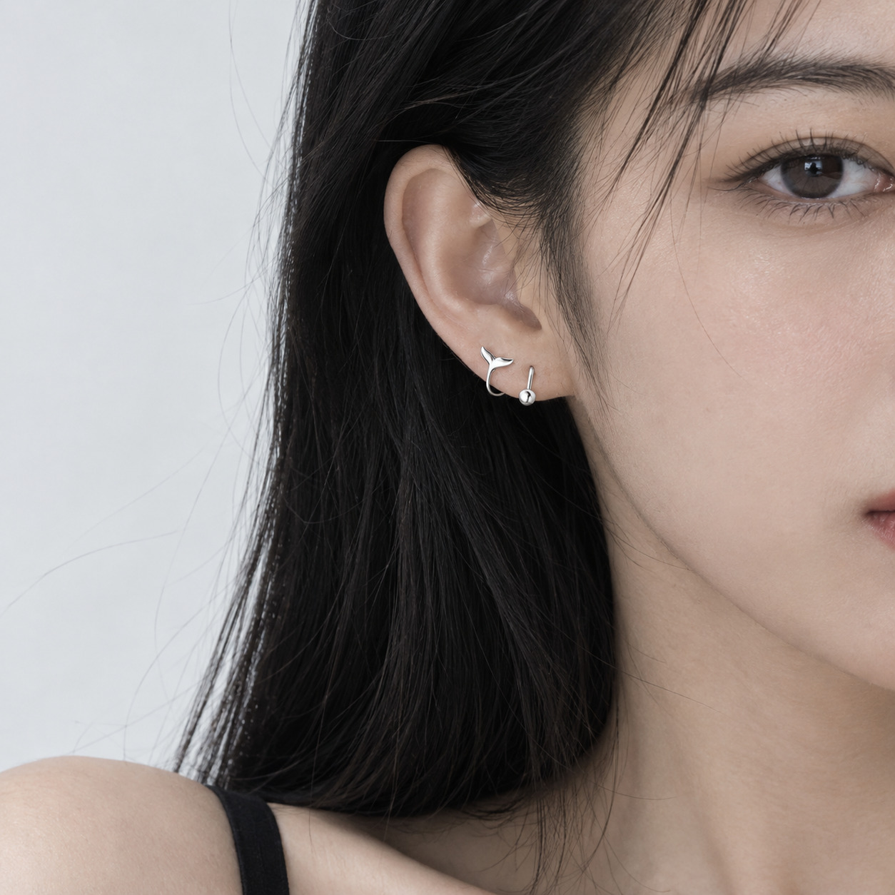 Close-up of a woman wearing Moana N°3 minimalist silver spiral ear studs
