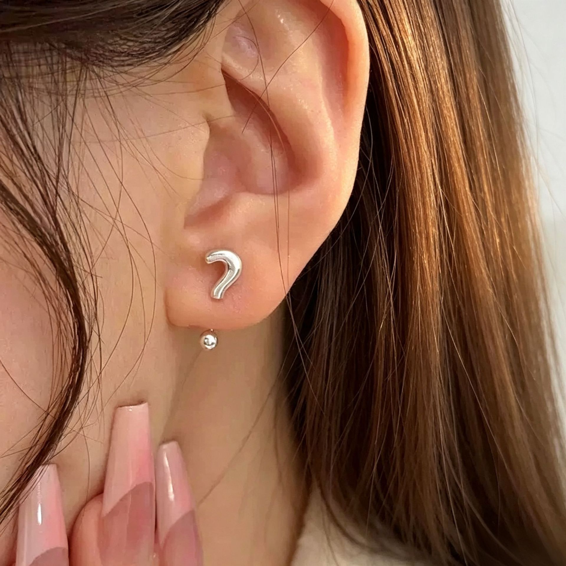 Punctuation inspired silver ear studs worn by woman