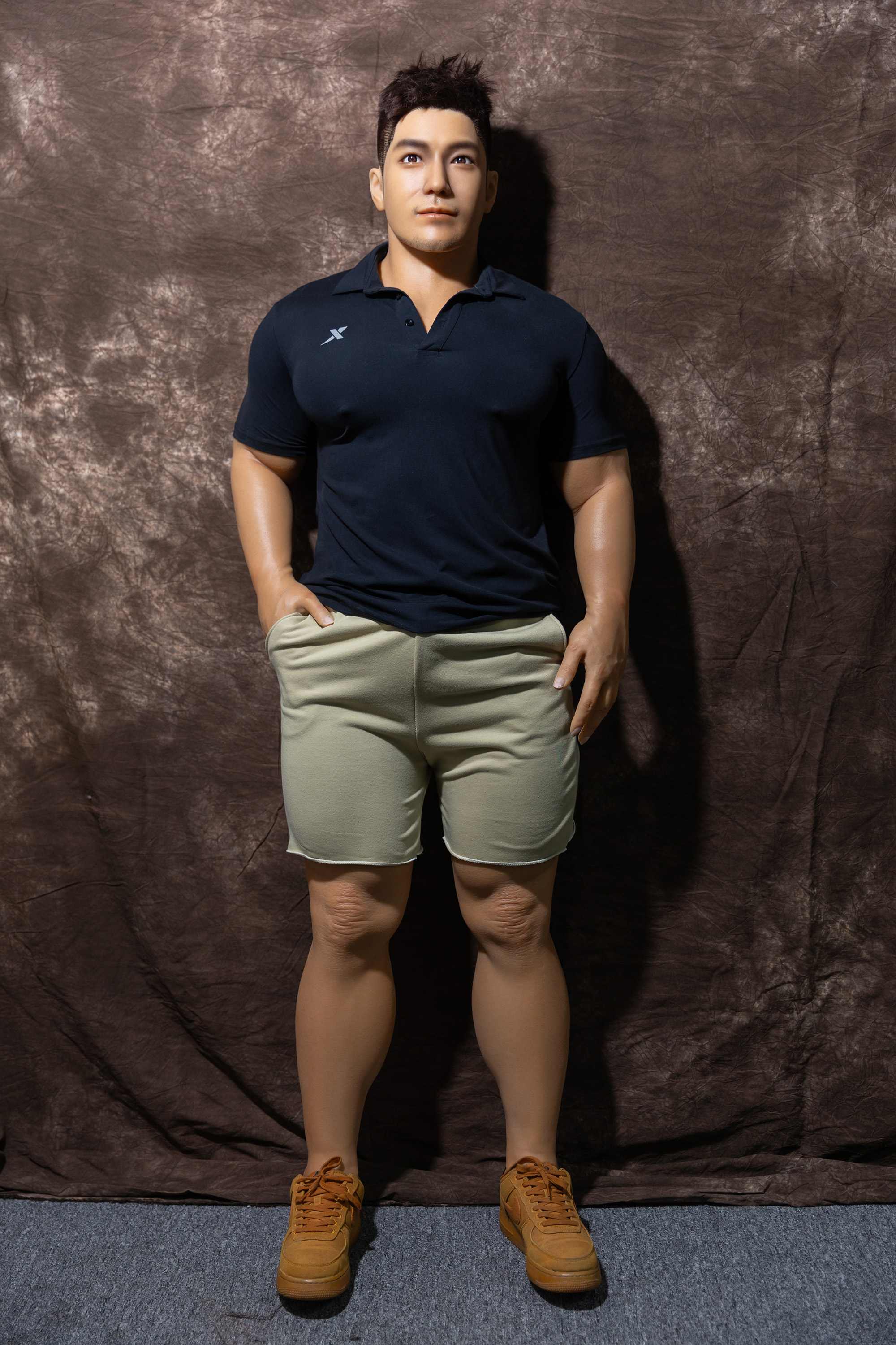 Male sex doll in navy polo shirt and beige shorts