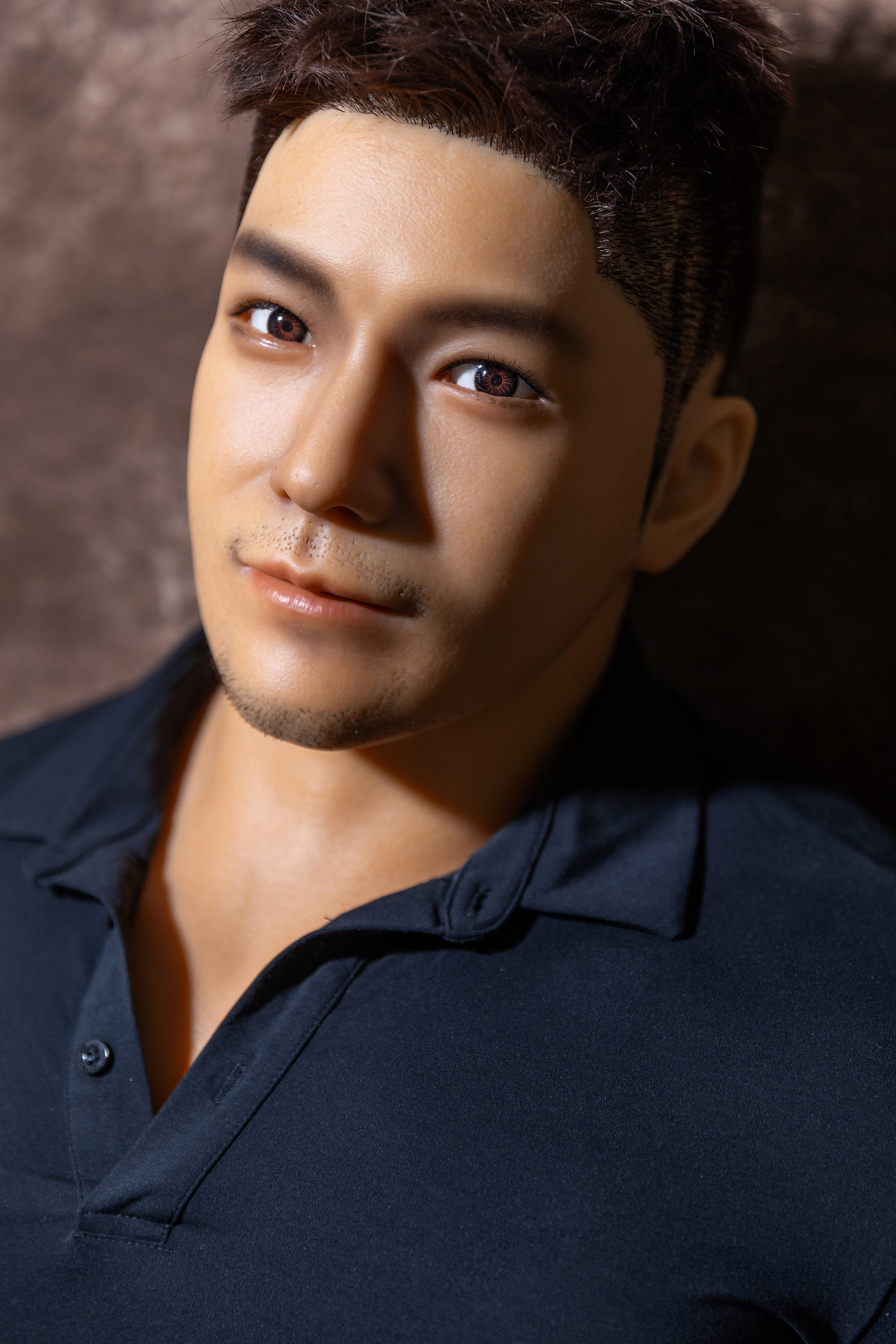 Close-up male sex doll face with realistic skin and stylish hair.