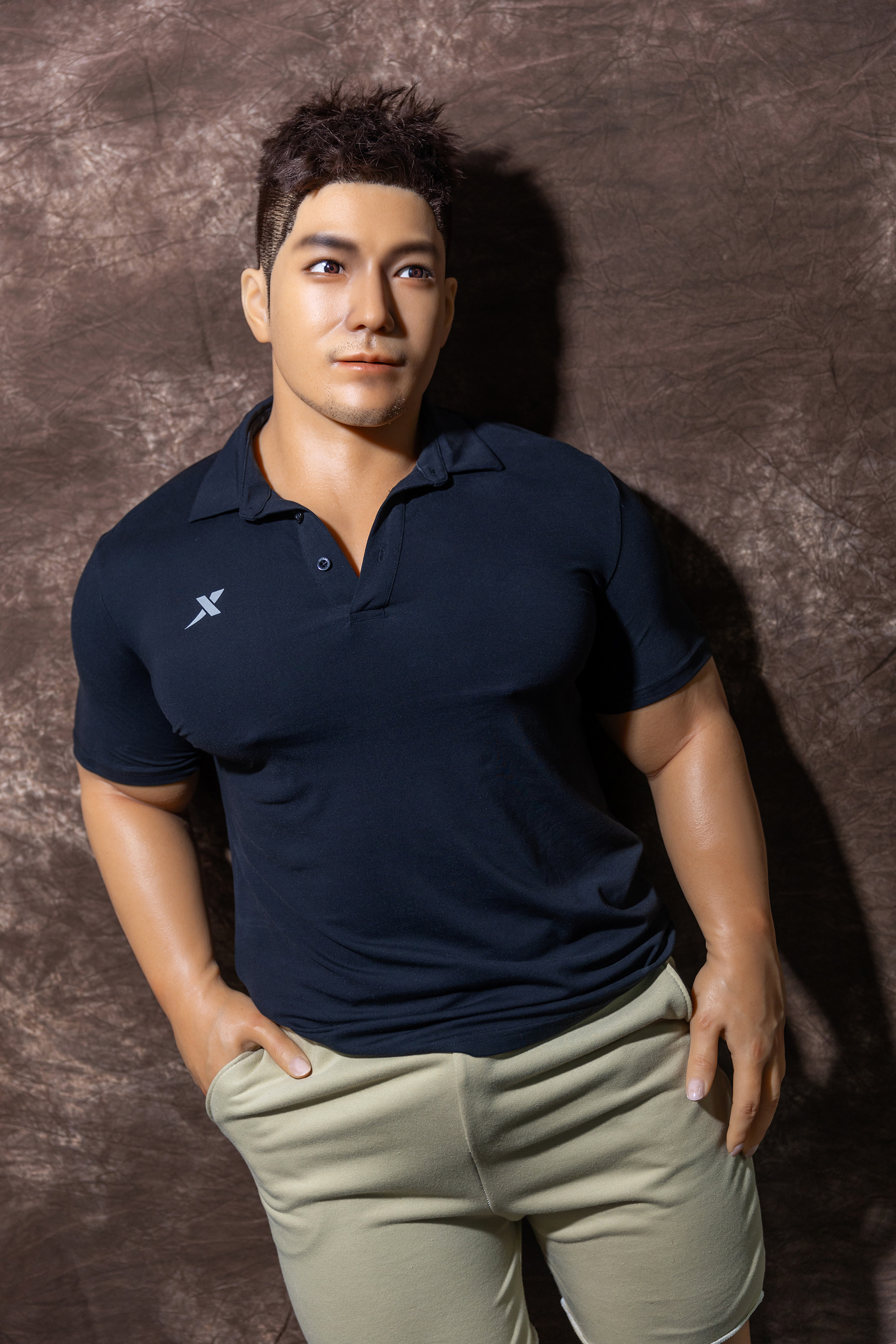Male sex doll in navy polo shirt and beige pants, seamless skin.