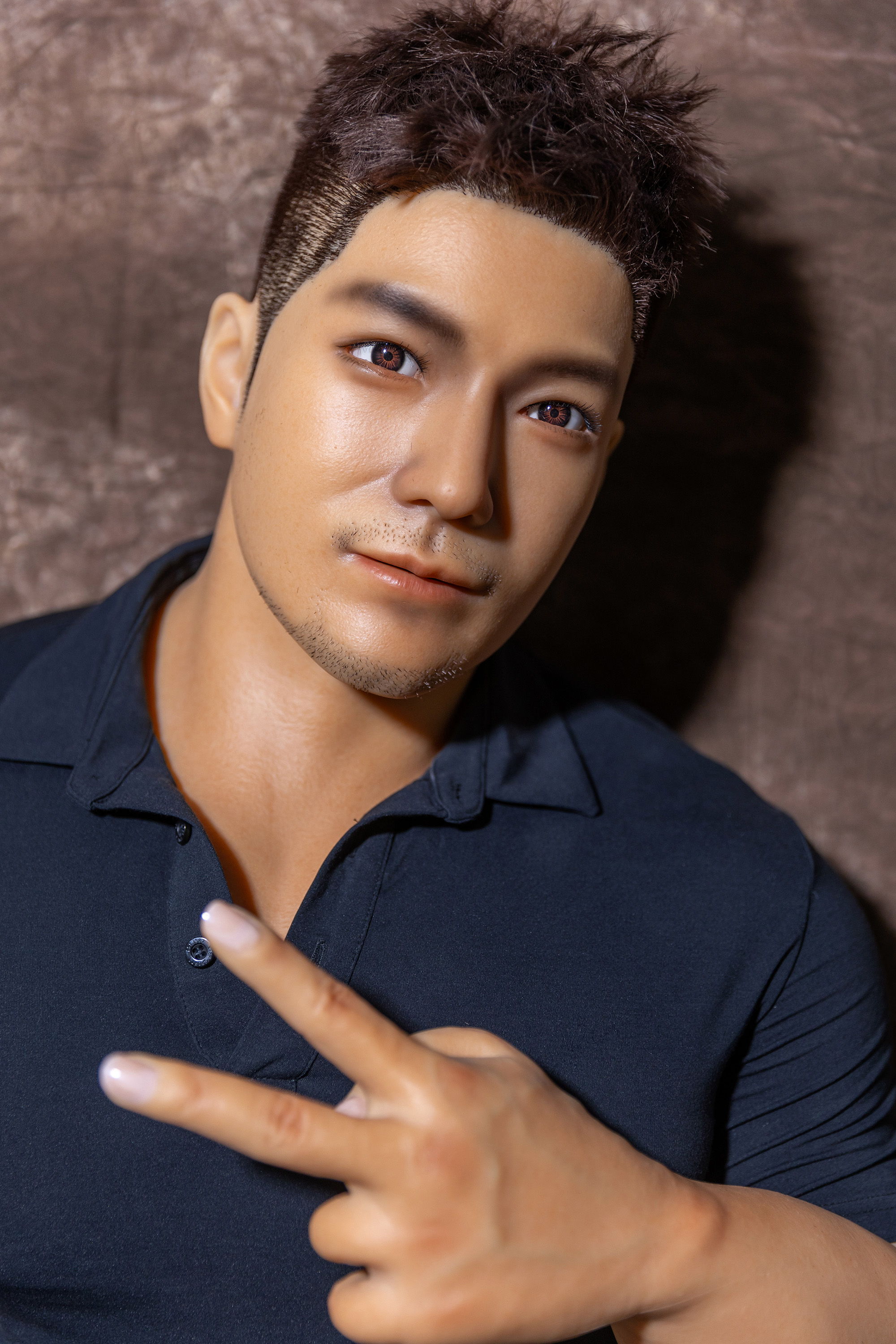 Male sex doll face and gesture, wearing black polo shirt