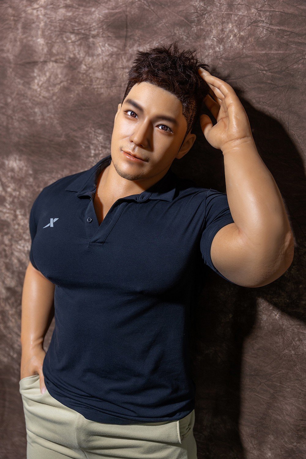 Male sex doll with stylish hair, navy polo shirt, beige pants