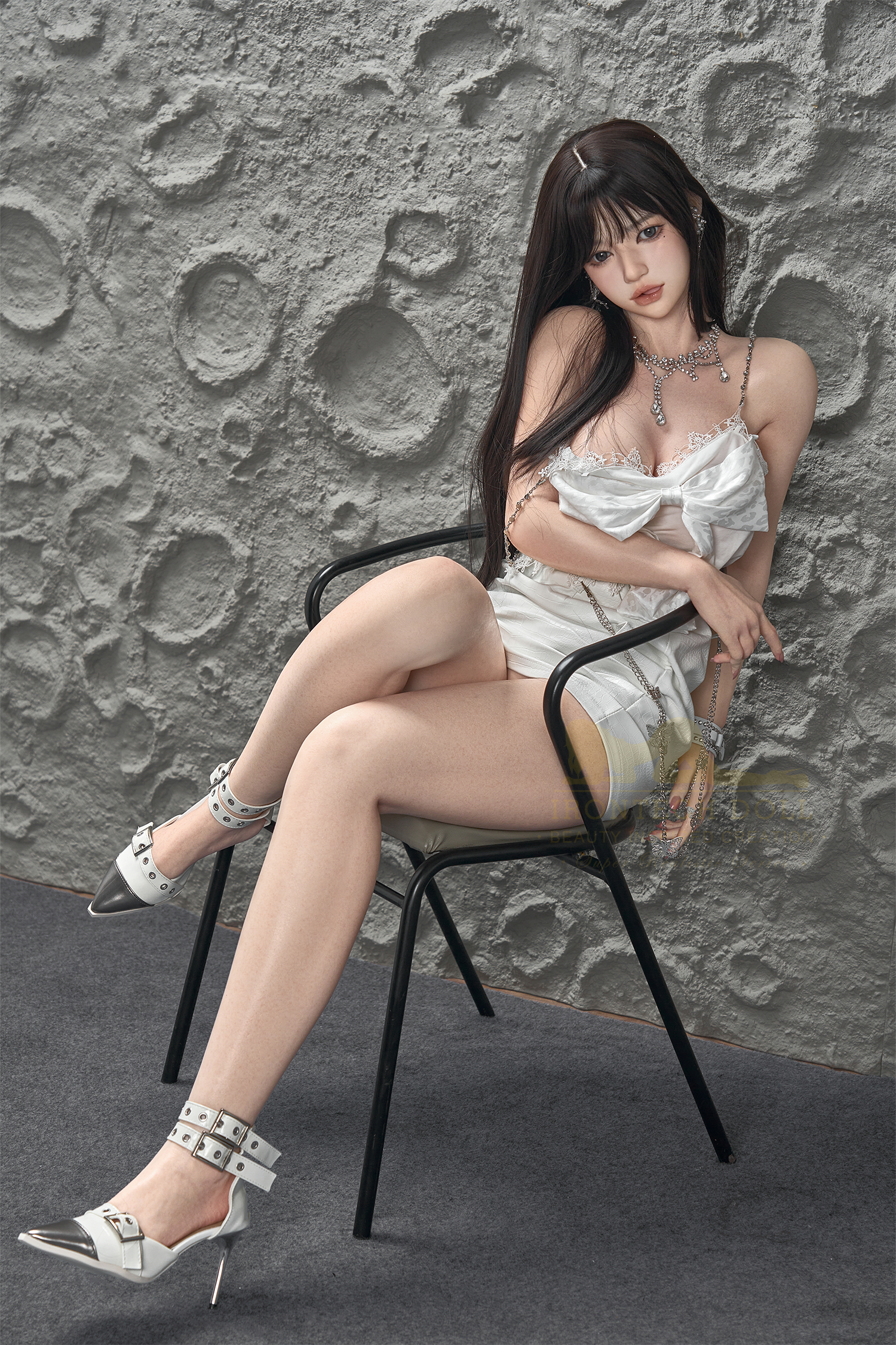 Evie Silicone Sex Doll in white dress, sitting on chair