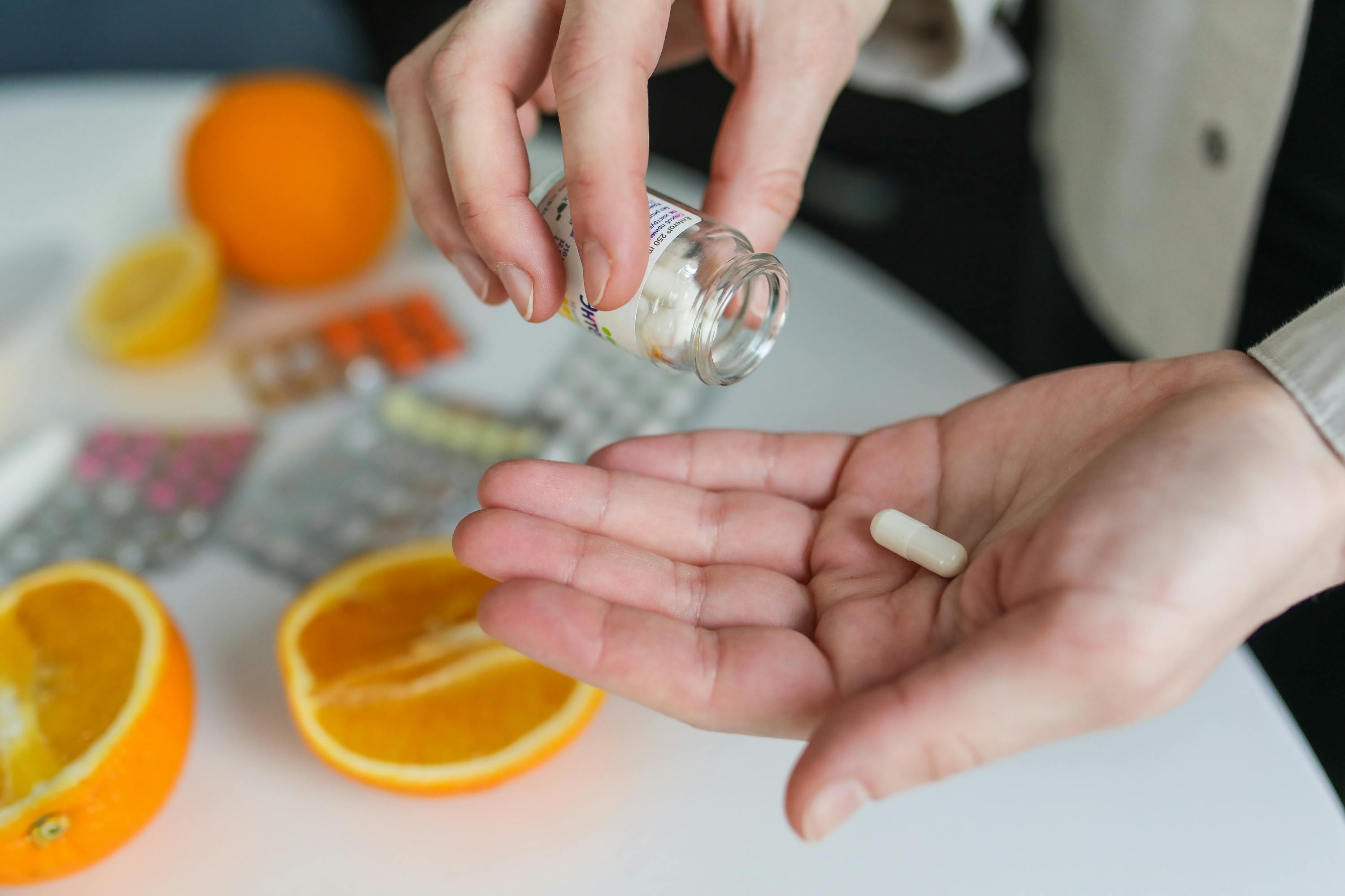 A person holding a supplement bottle and pouring out capsules into his hand