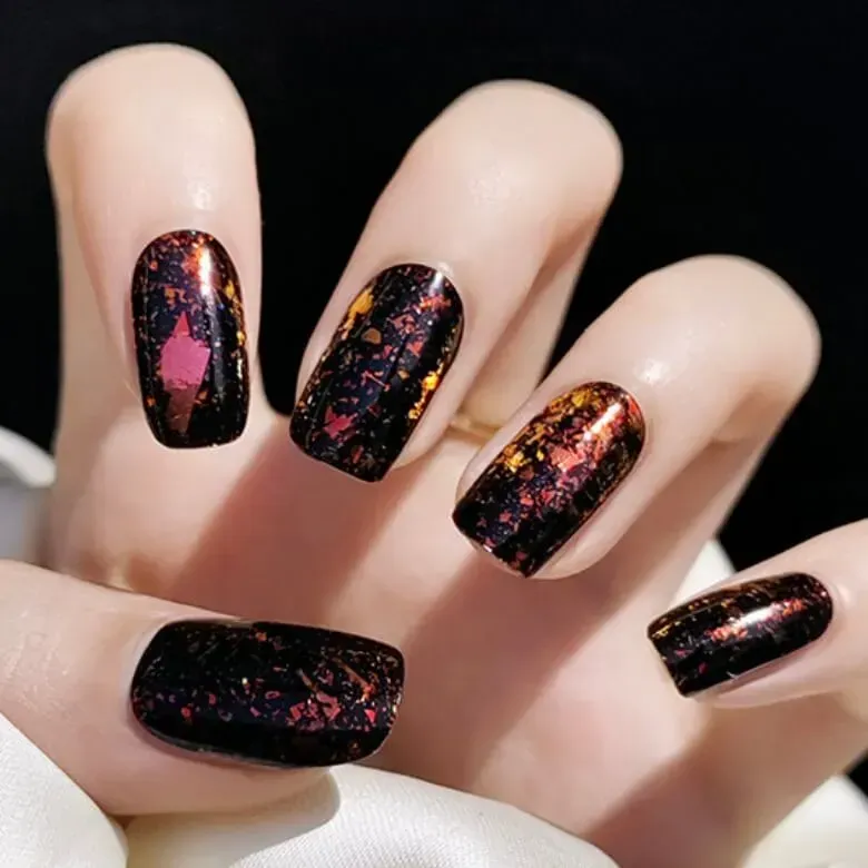 Autumn Fire Gel Nail Wraps with a bold black base and shimmering orange and gold metallic flakes for a fall-inspired manicure.