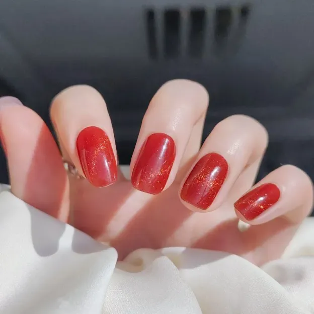Shimmer red gel nail wraps with a glossy and sparkly finish for an elegant DIY nail art look.