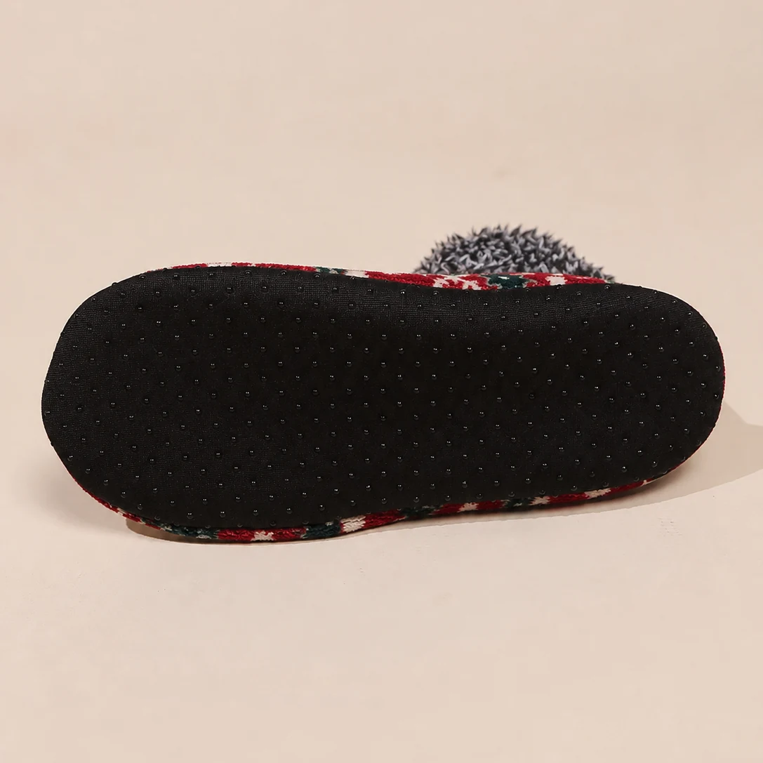 Close-up of black dotted grip sole on a Christmas fuzzy house sock