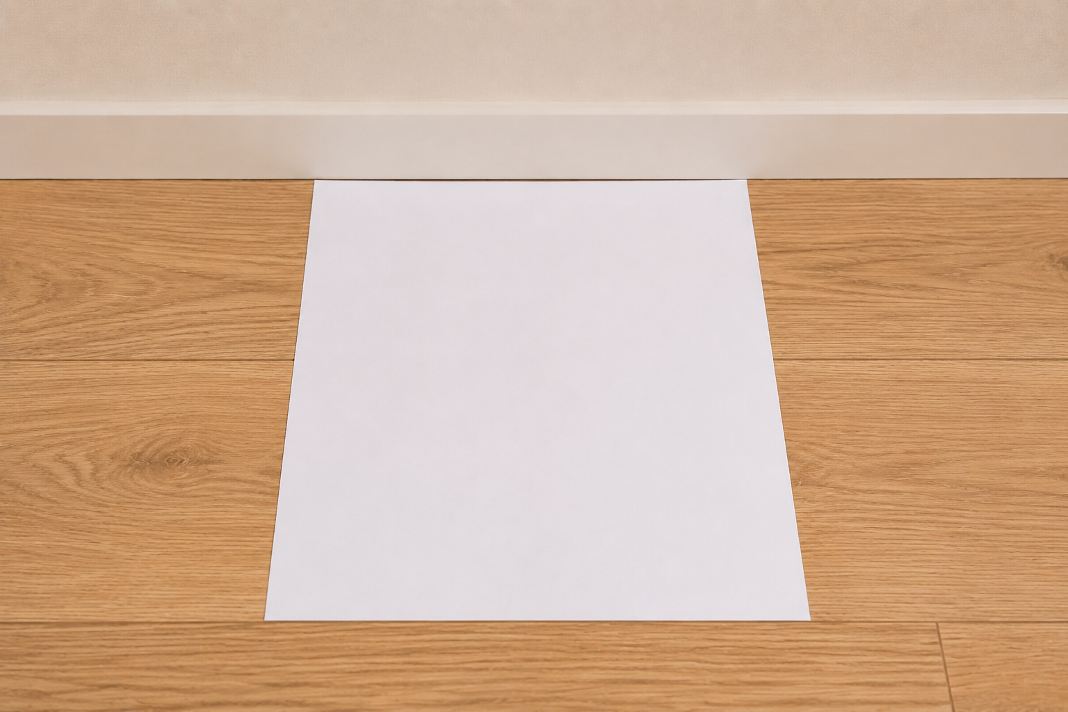 A sheet of paper placed flat on the floor against a wall