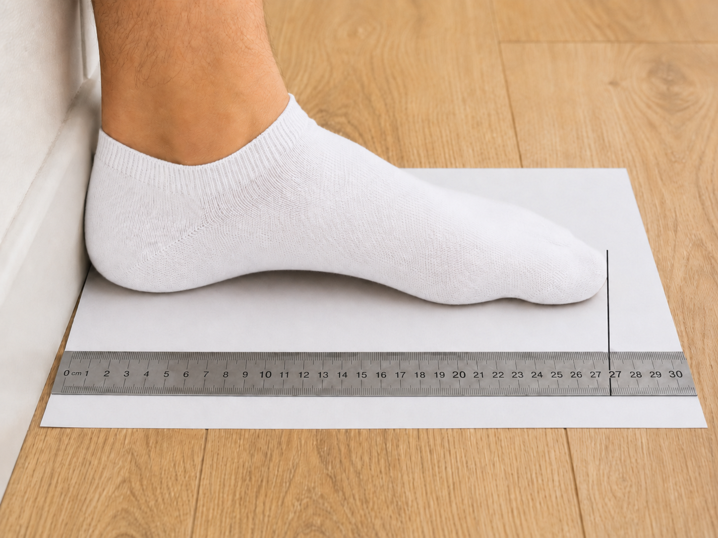 Measuring from the wall edge to the longest toe mark with a ruler