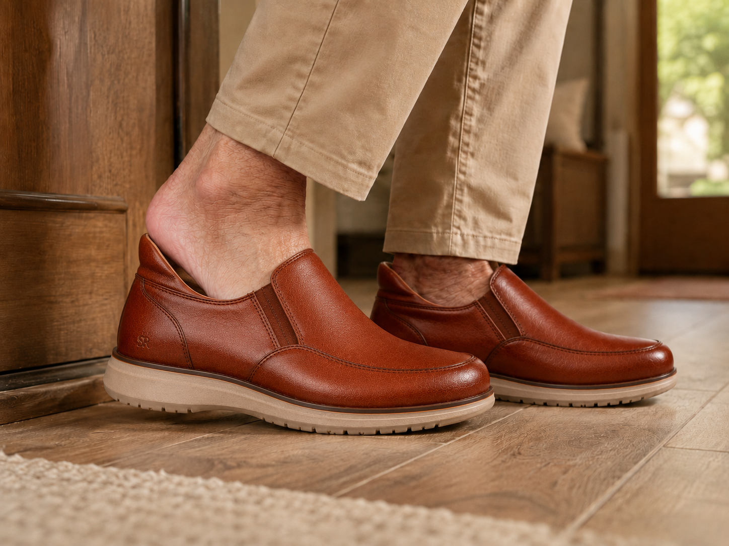 Mature man stepping into StepReady brown leather loafers at home without using hands