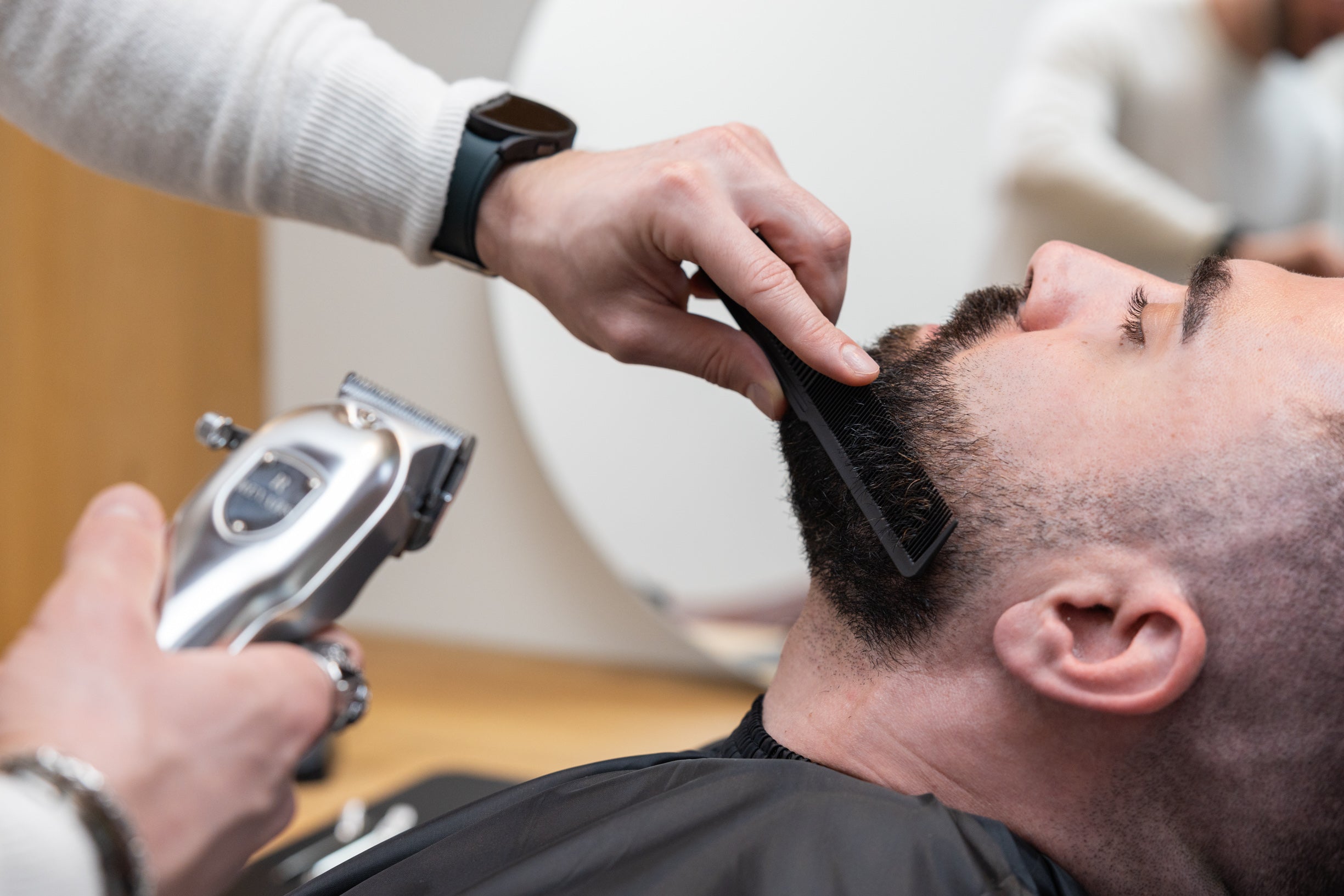 Man die zijn haar knipt met de Revahs Clipper One haartondeuse en opzetkam voor een precieze en schone snit.