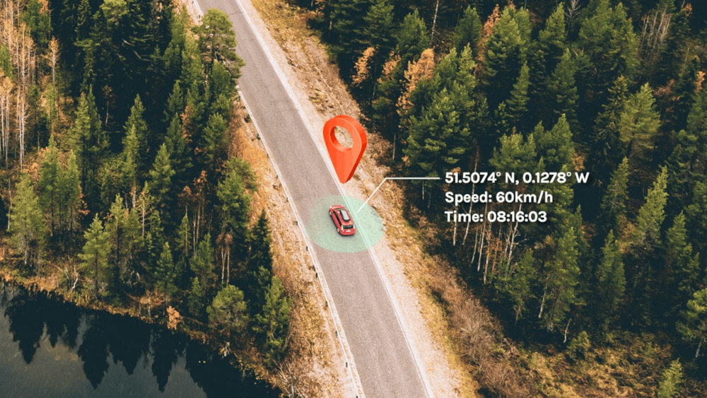 A fot&oacute; egy aut&oacute;t mutat erdőszeg&eacute;lyes &uacute;ton, r&aacute;vet&iacute;tett GPS adatokkal: 51.5074&deg; &Eacute;, 0.1278&deg; Ny, sebess&eacute;g 60 km/h, idő 08:16:03. Az aut&oacute; felett piros helyzetjelző ikon l&aacute;that&oacute;.