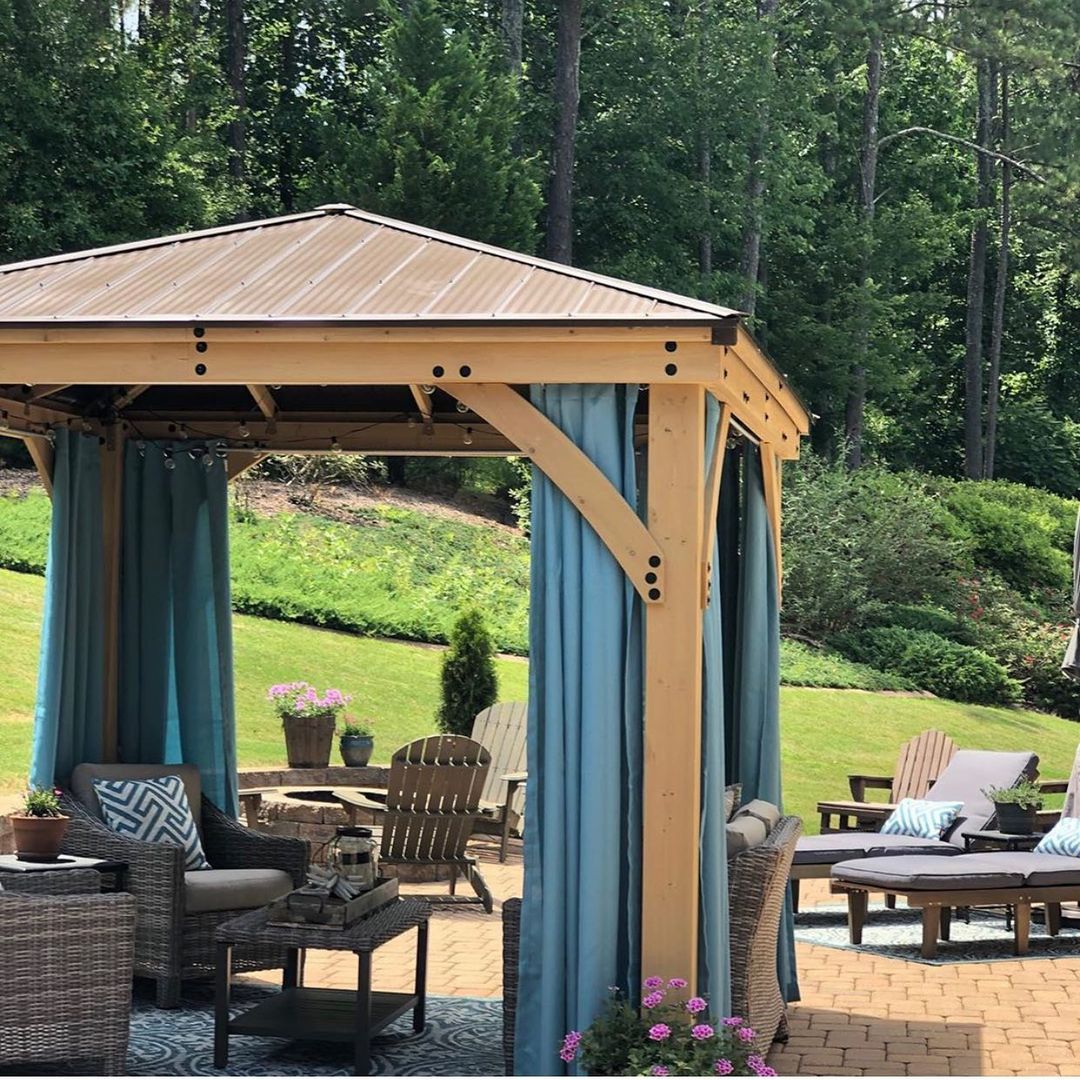 Blue Outdoor Curtains hanging from a wood pergola beside a furnished patio