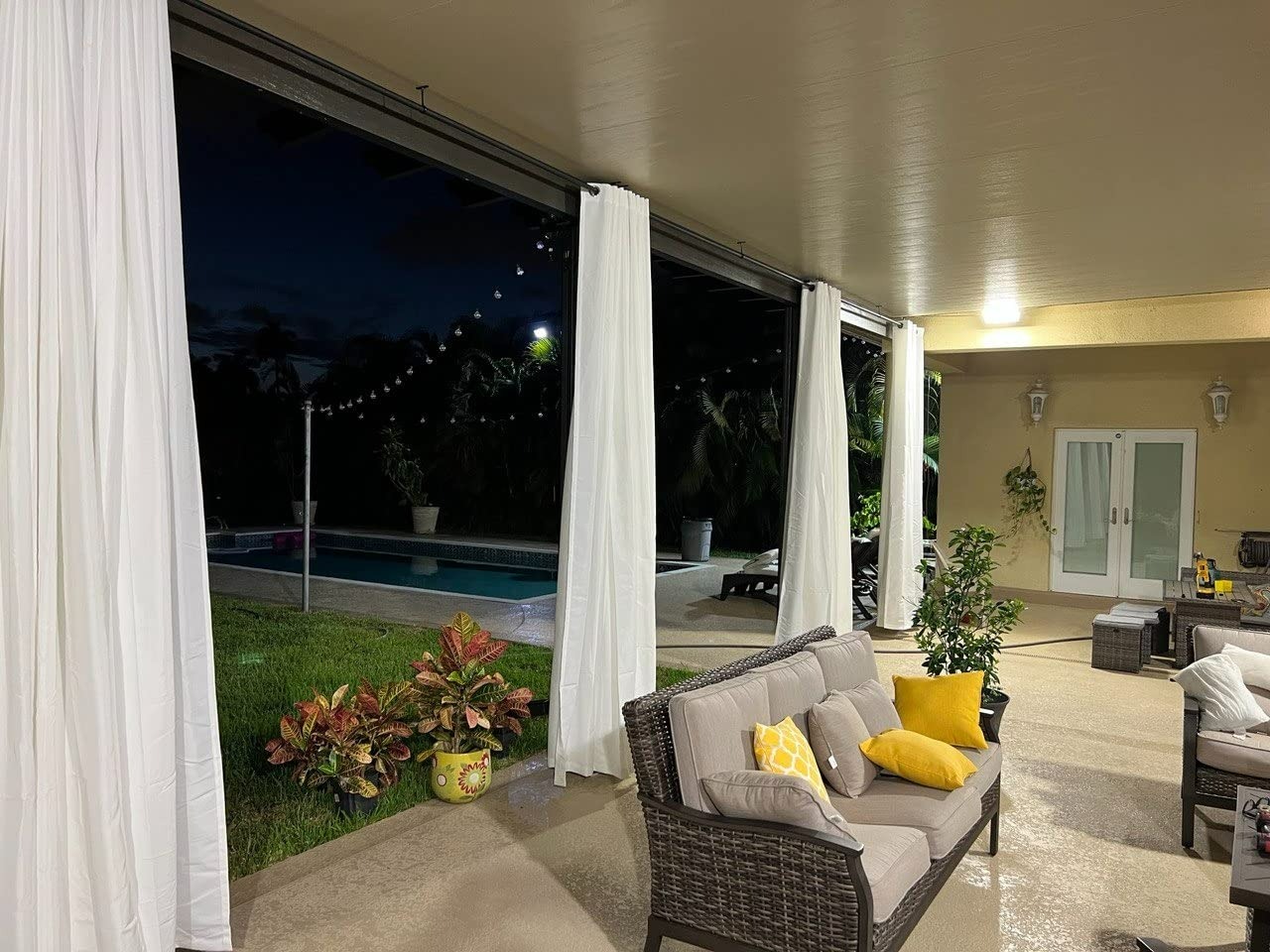 Grommet outdoor curtains hanging from a rod on a covered patio