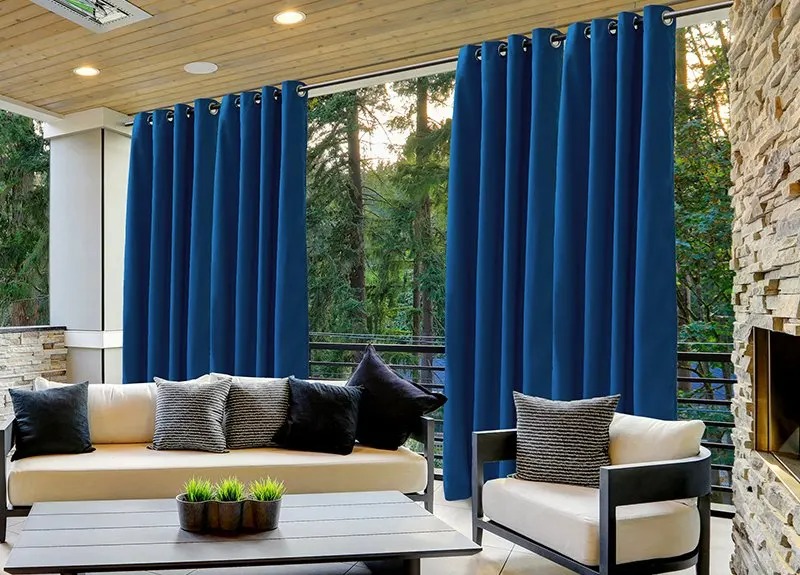 Blue outdoor curtain panels hanging on a covered patio