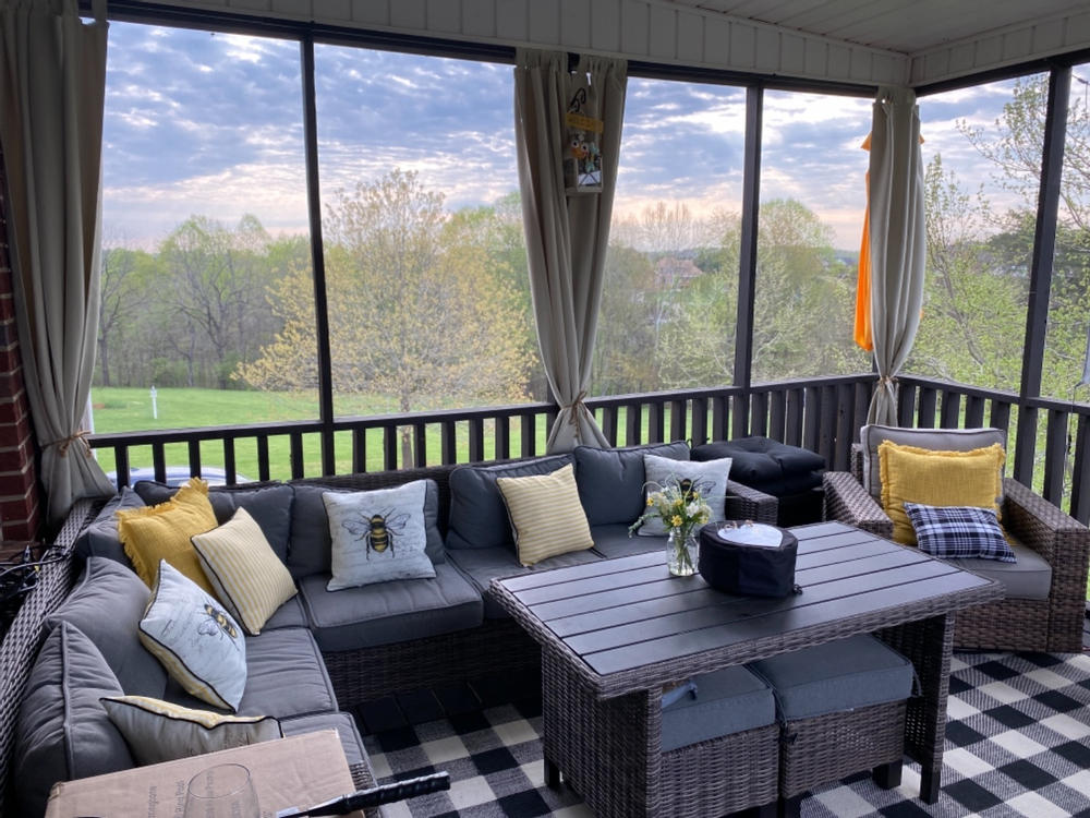 Light outdoor curtains tied back around a screened porch seating area