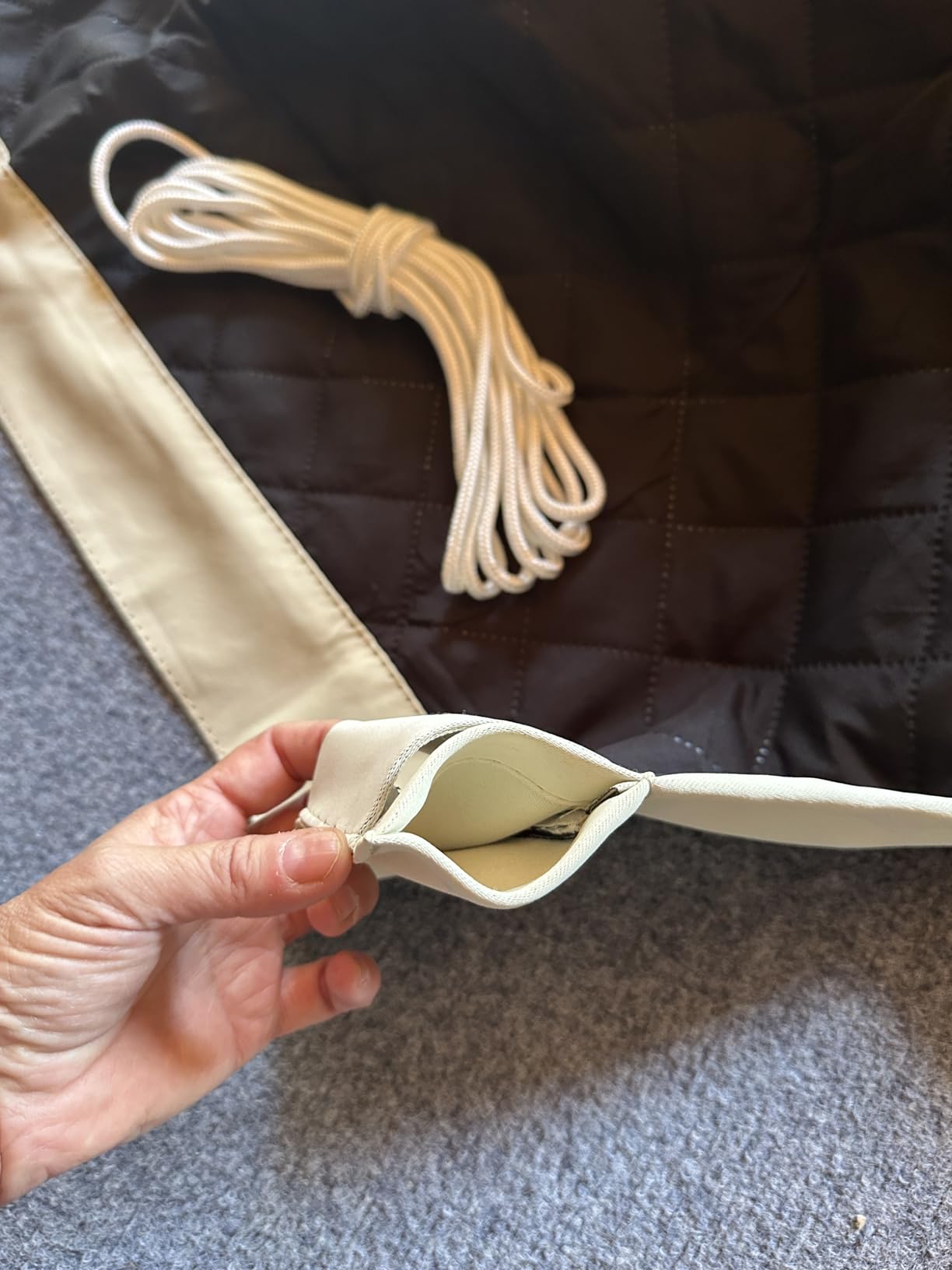 Close-up of the layered edge and tie cord of a beige insulated outdoor curtain