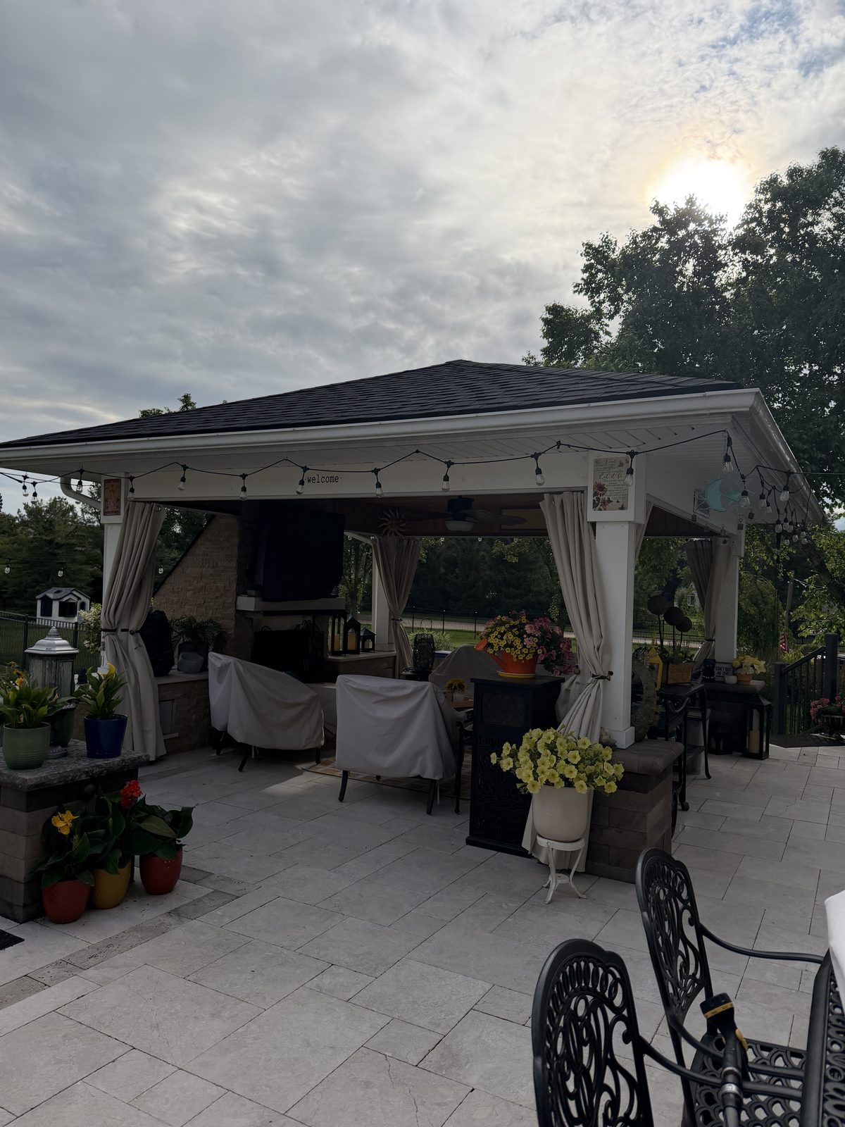 Snowcity outdoor curtains installed around a covered backyard pavilion patio with string lights and flowers