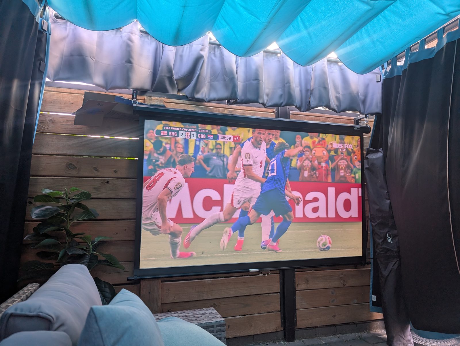 Dark Snowcity outdoor curtains around a patio TV and projector screen during daytime