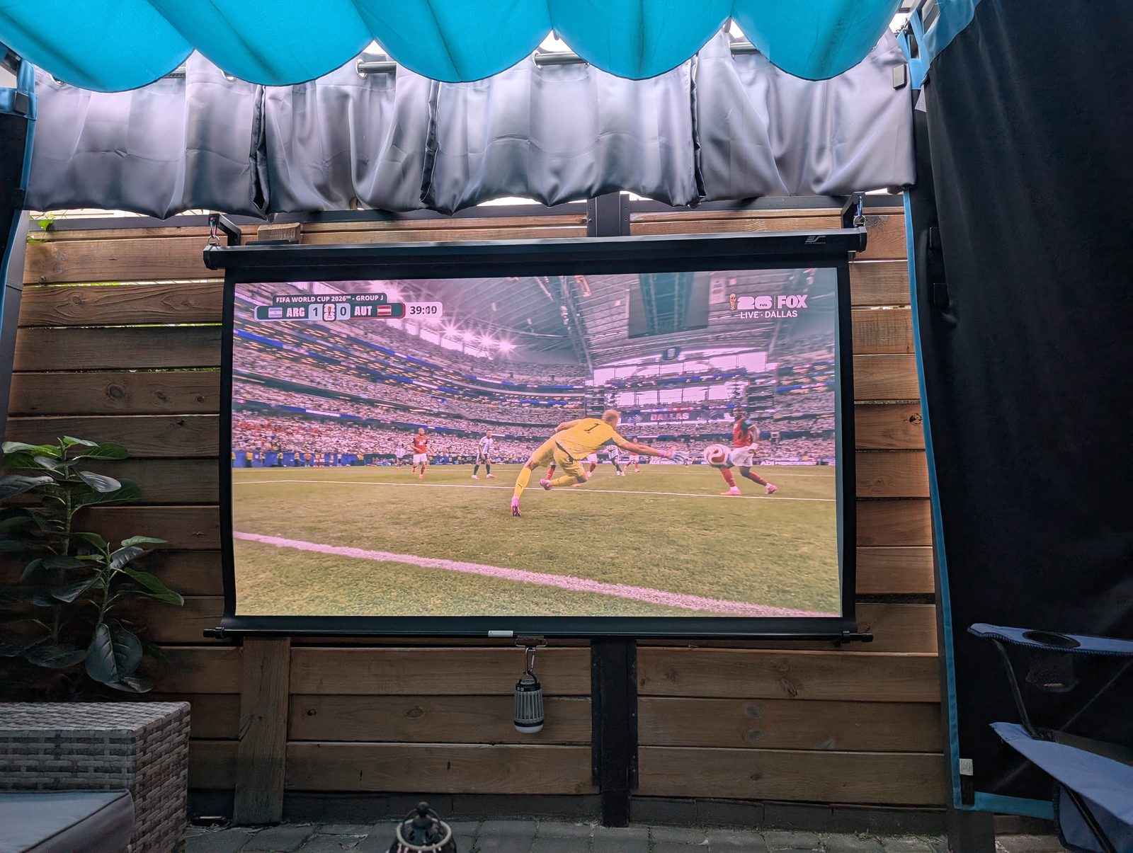 Snowcity patio curtains framing an outdoor projector screen with wood fence and seating area