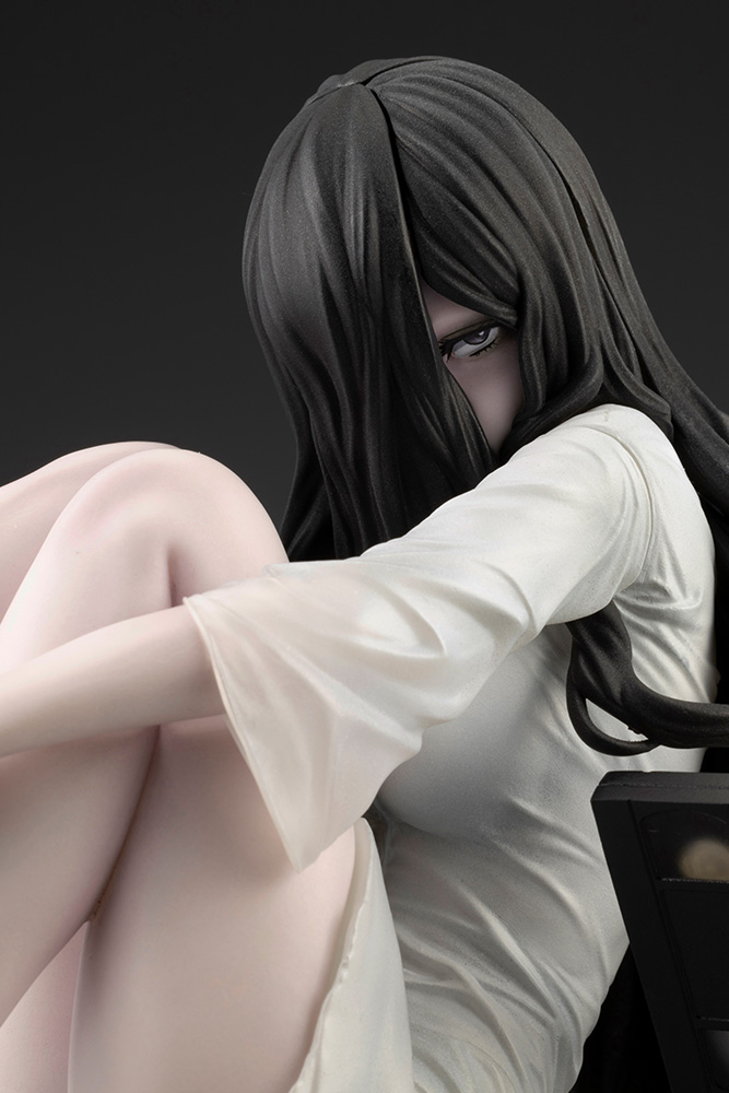 Close-up of the Sadako figure with one eye peeking out through her long black hair above her knees
