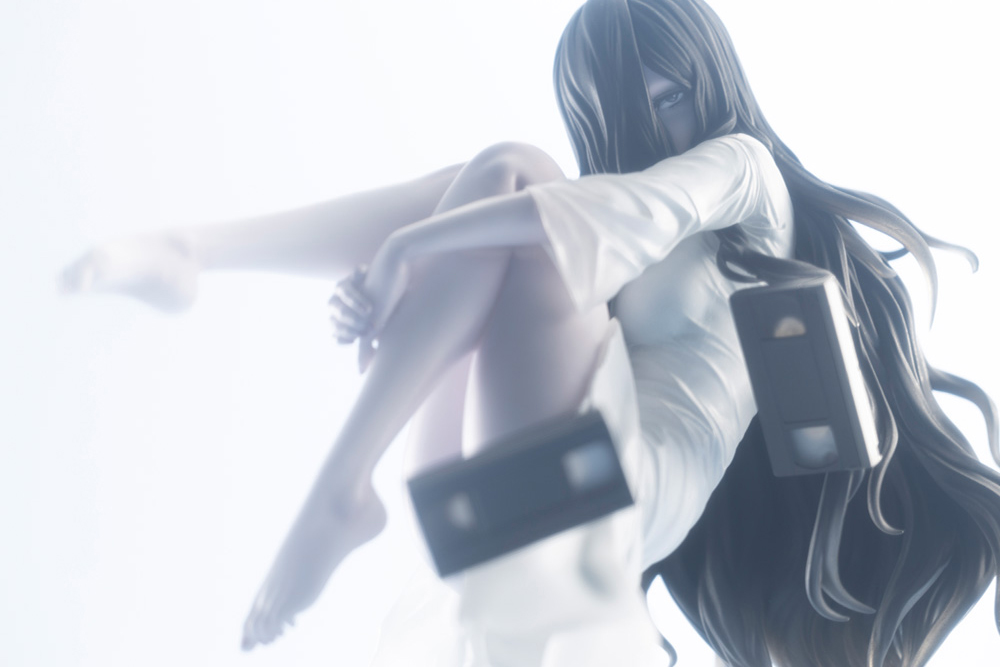 Atmospheric photo of the Sadako figure in soft white light holding a videotape as she floats in mid-air